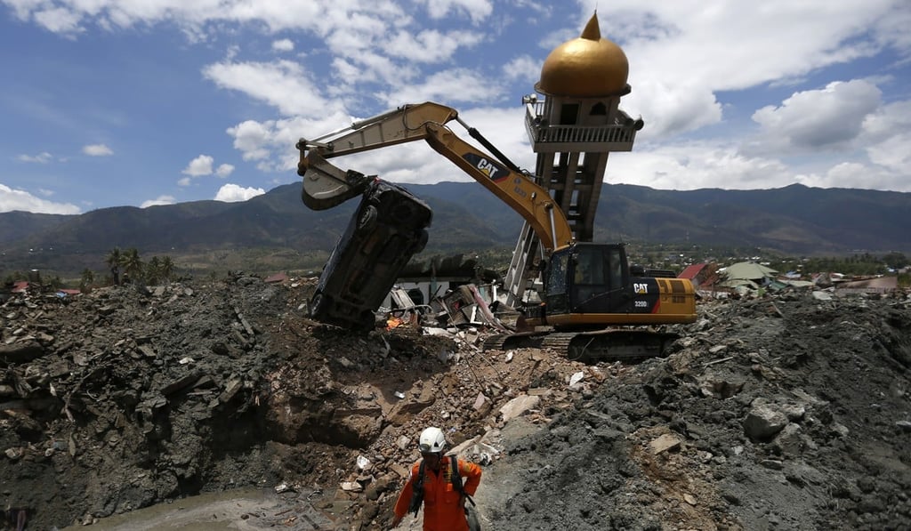 A heavy machine removes a car during a search for earthquake victims in October. Photo: AP