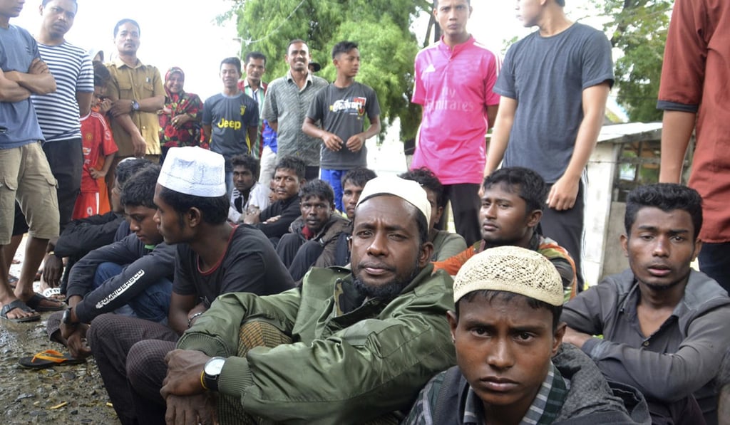 Rohingya men who were rescued by local fishermen sit on the ground in Kuala Idi, Aceh province, Indonesia. Photo: AP