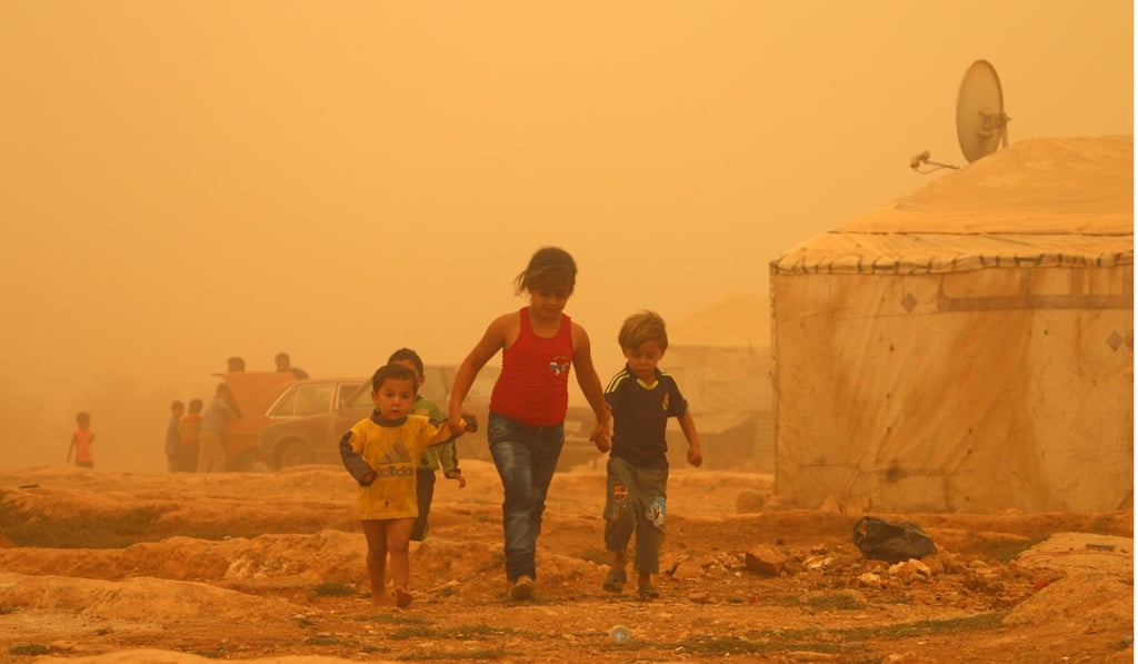 Syrian children walk through a sandstorm in a Lebanese refugee camp. Picture: AFP Syrian children walk through a sandstorm in a Lebanese refugee camp. Picture: AFP