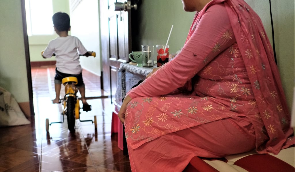 Shazee rides his bike out into the landing outside his family's small rented room in Bangkok as his mother, Sherry, looks on. Photo: Tibor Krausz