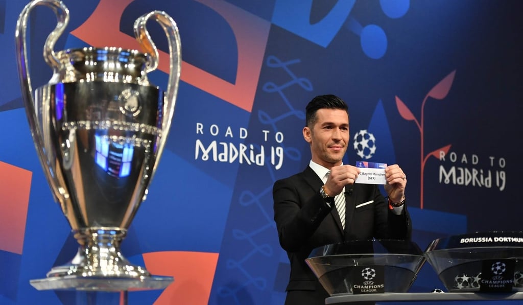 Former Spanish football player Luis Garcia shows the slip of Bayern Munchen next to the cup. Photo: AFP