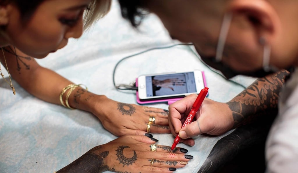 Former porn star Mana Izumi gets a new tattoo design on her fingers. Photo: AFP