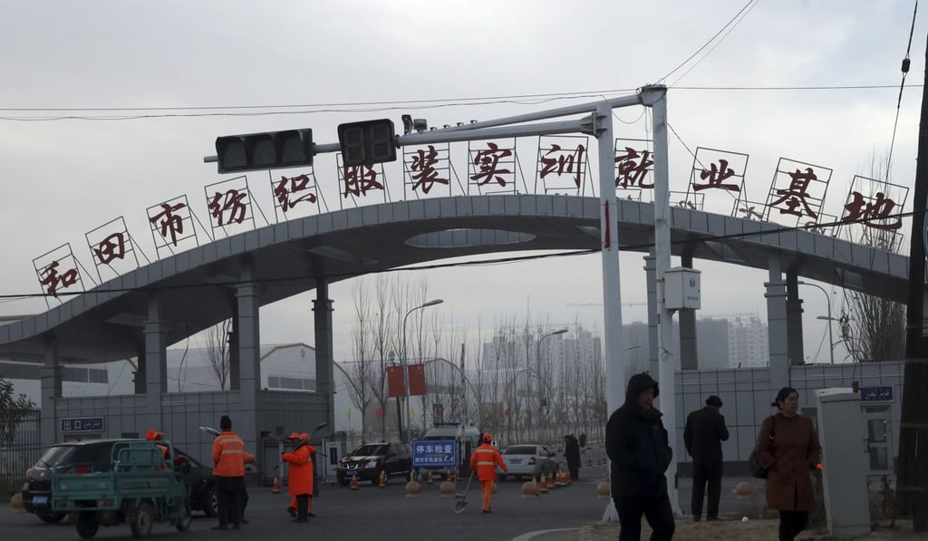 Residents pass by the entrance to the Hotan City apparel employment training base, where Hetian Taida has a factory. Photo: AP Residents pass by the entrance to the Hotan City apparel employment training base, where Hetian Taida has a factory. Photo: AP