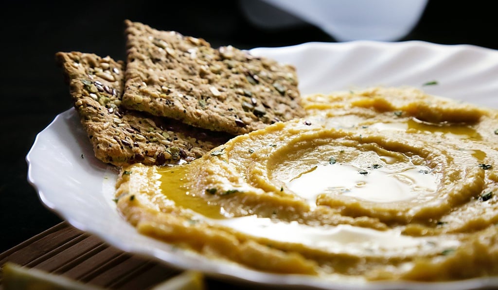 Home-made hummus with lemon, herbs and virgin olive oil and served with multi-seed flatbread makes a healthy snack. Home-made hummus with lemon, herbs and virgin olive oil and served with multi-seed flatbread makes a healthy snack.