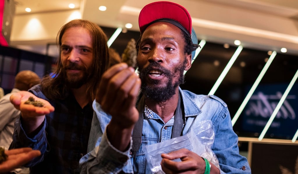 Rastafarian Steven Thapelo Khunou (right) hands out marijuana to visitors outside the Cannabis Expo as marijuana is not allowed inside the expo. Photo: AFP