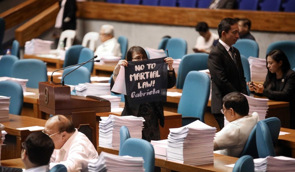 A woman holds a cloth placard displaying opposition to martial law during the joint session at the Philippine Congress in Quezon City on December 12. Photo: EPA-EFE