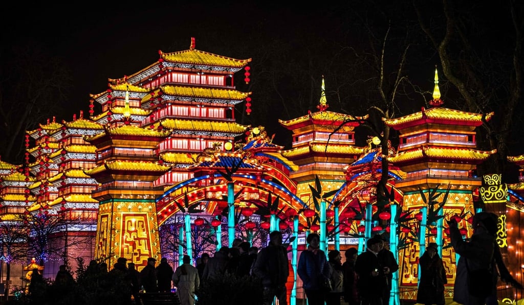 Visitors stand in front of monumental silk lanterns depicting a palace. Photo: AFP Visitors stand in front of monumental silk lanterns depicting a palace. Photo: AFP
