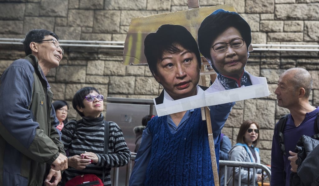 A protester holds a placard of Hong Kong's justice secretary Teresa Cheng and Chief Executive Carrie Lam during a march on February 11, calling for Cheng to step down over illegal structures found at the homes she owns. Lam refused to rescind her nomination. Photo: AFP
