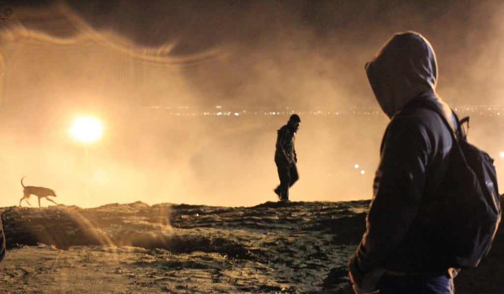 Migrants try to avoid tear gas used by US border officers near Tijuana. Photo: EPA