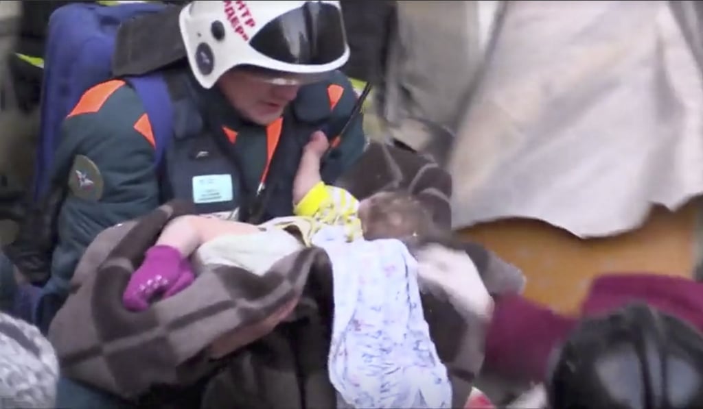 A rescuer carries a 10-month-old child found alive in the rubble of a Russian apartment block that partially collapsed after a suspected gas blast in Magnitogorsk, Russia January 1, 2019. Photo: Handout via Reuters