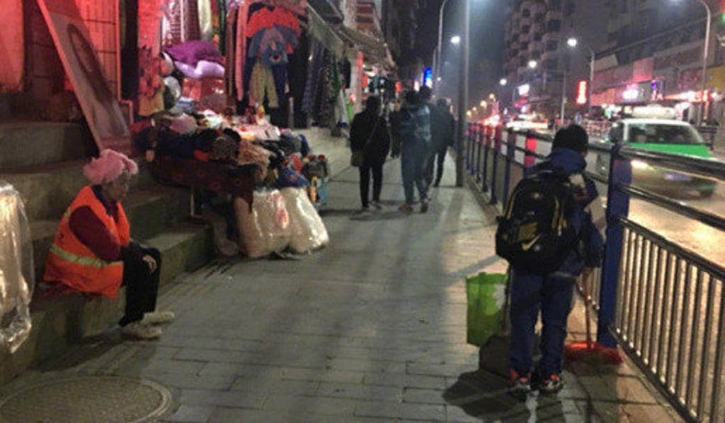 Long Guotao sweeps while his mother rests nearby on a street in Kaili, Guizhou province. Photo: Weibo
