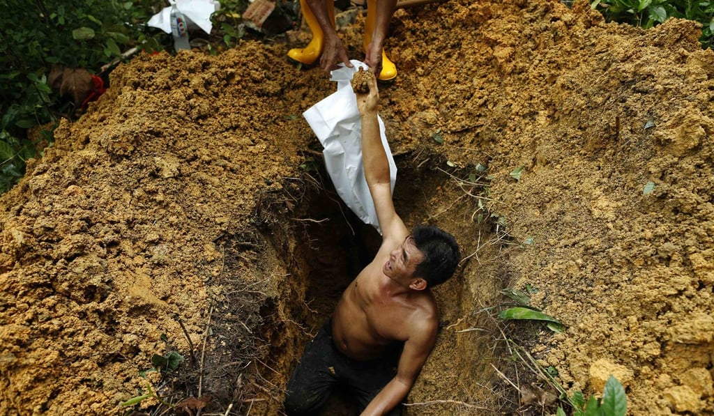 A grave digger hands over coffin nails found when exhuming a grave at Bukit Brown Cemetery in Singapore. Photo: Reuters