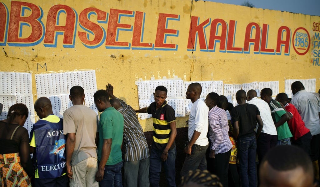 Election officials tape voter registration lists to a wall at a school in Kinshasa, Congo. Photo: AP