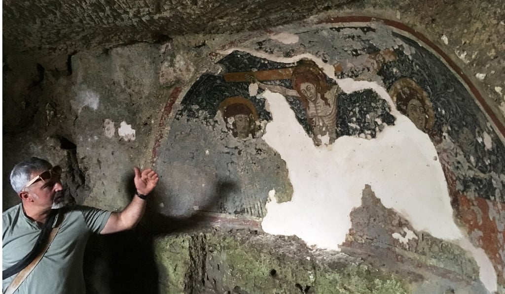 Tonio Creanza is founder and director of Messors. Next to him is a fresco of the crucifixion in the crypt of Carpentino in Altamura. Photo: Ben Yagoda for The Washington Post