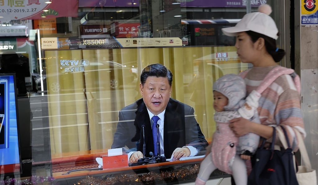 A mother carries her child past a television in New Taipei City showing Xi Jinping’s speech calling for unity. Photo: AFP A mother carries her child past a television in New Taipei City showing Xi Jinping’s speech calling for unity. Photo: AFP