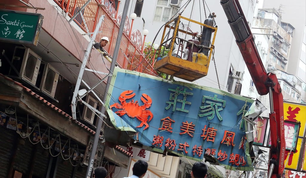 A restaurant signboard on Temple Street in Jordan is taken down in May 2015. Photo: Felix Wong