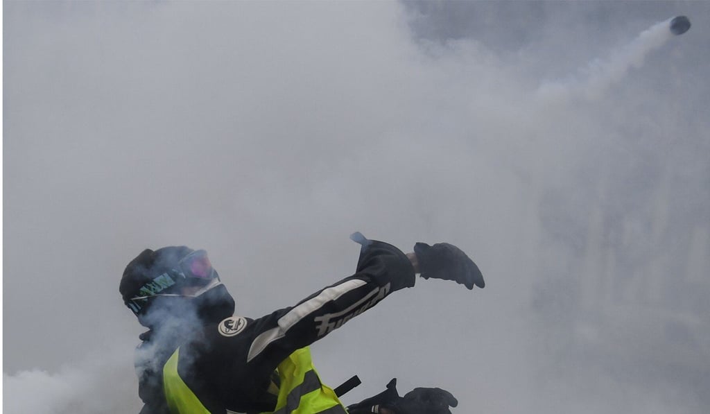 A protester throws back a tear-gas canister at riot police in Bourges. Photo: AFP