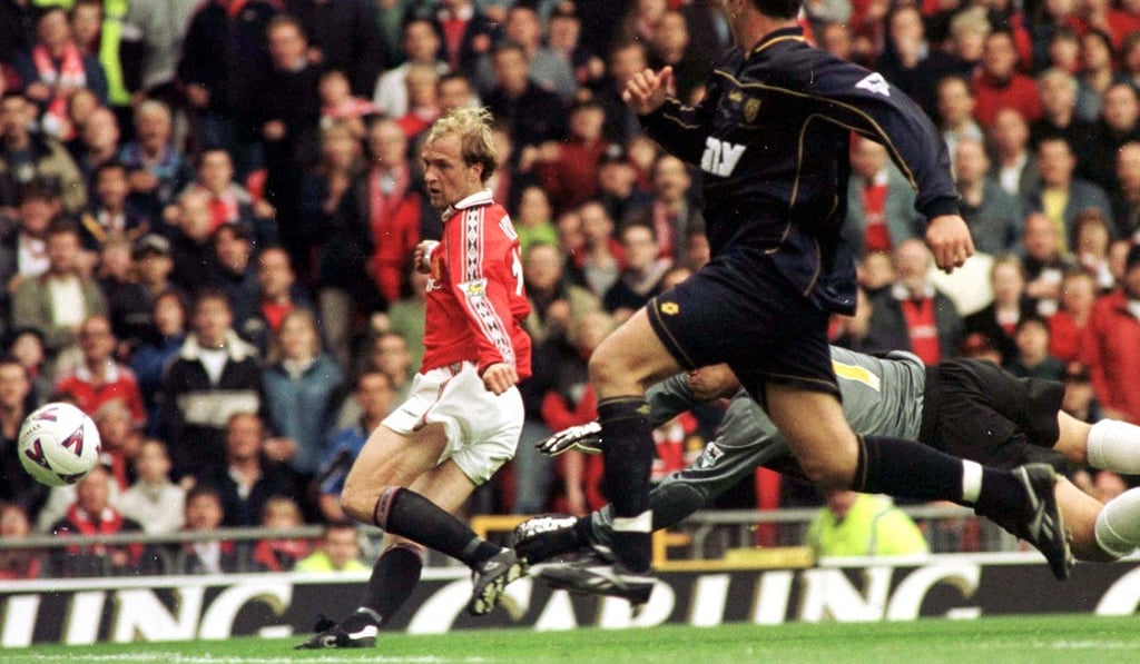 Jordi Cruyff (left) puts the ball past Wimbledon goalkeeper Neil Sullivan in 1999. Photo: AP