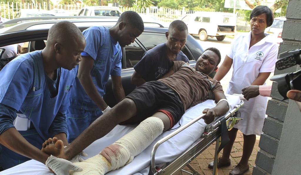 An injured man is helped at a private hospital on Thursday after an alleged assault by a group of uniformed soldiers in Harare, Zimbabwe. Photo: AP
