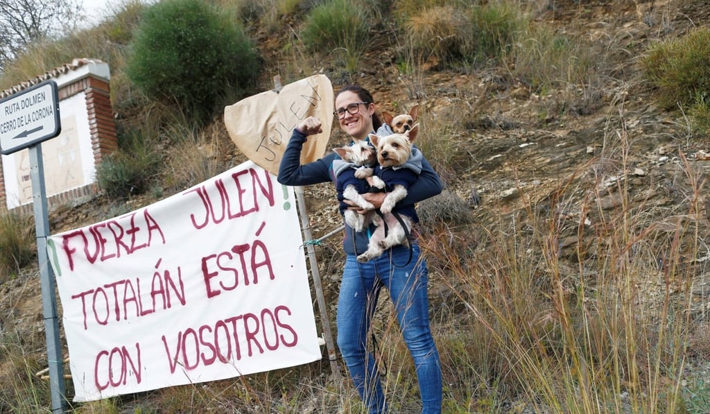 Maria Guarrochena with her dogs next to a banner offering support to Julen. Photo: Reuters