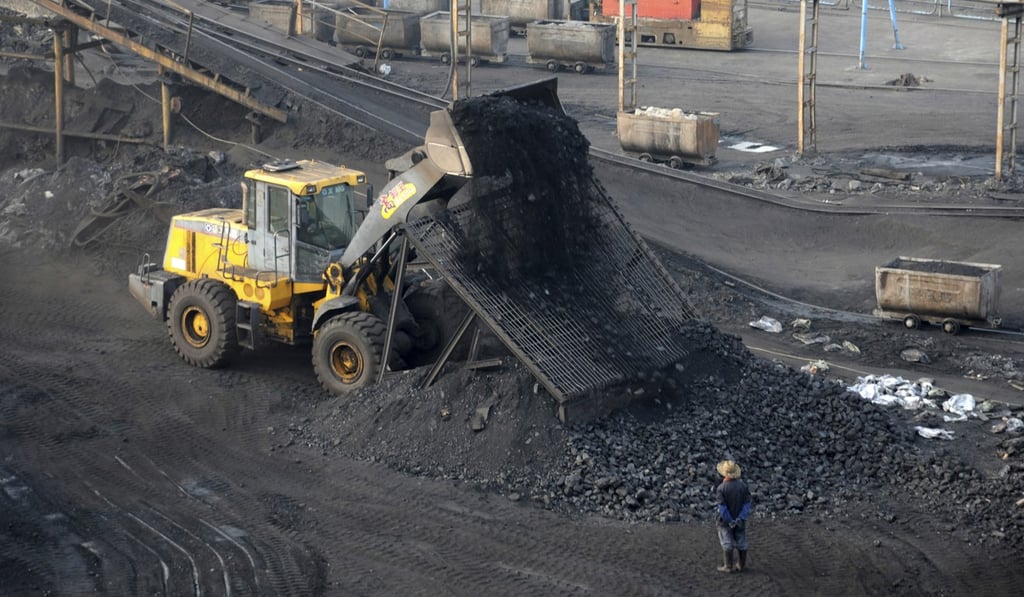 A worker watches as a digger dumps a load of coal at a mine in Huaibei in central China’s Anhui Province in February 2017. China aims to move away from coal as an energy source and is investing heavily in renewable energy. Photo: AP
