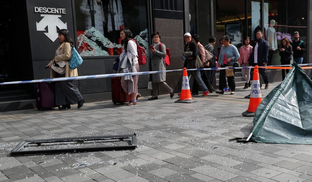 Pedestrians walk past the shattered glass from a window that fell and killed a woman in Tsim Sha Tsui on Monday. Photo: Edmond So