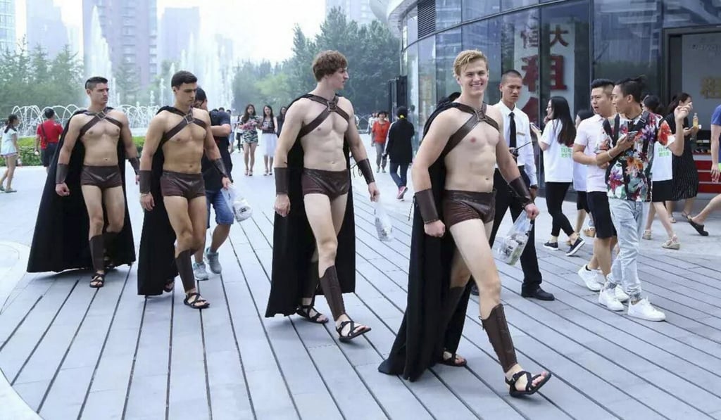Half-naked male foreign models dressed in costumes of Spartan warriors march along a street during an anniversary promotional campaign in China. Photo: Imaginechina