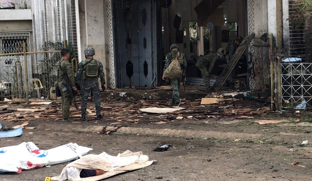 Filipino soldiers cover the bodies of victims at a cathedral in Jolo where two bombs exploded, killing more than 20 people. Photo: EPA