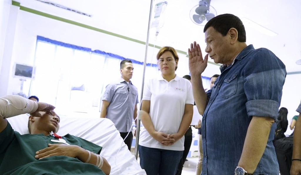President Rodrigo Duterte, right, salutes a soldier wounded by Sunday’s explosion, during a visit to a military camp in Jolo. Photo: EPA