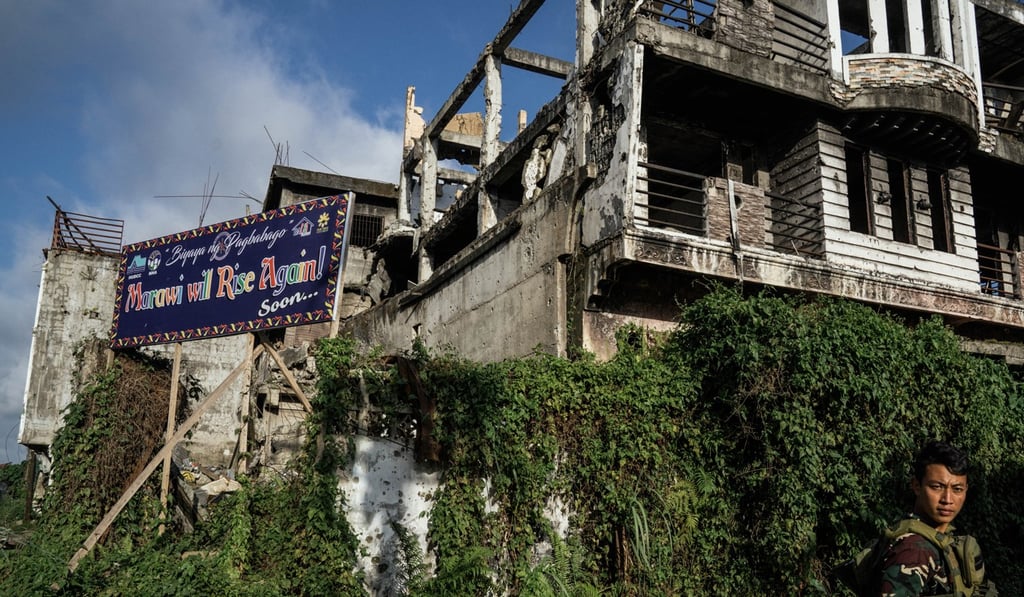 A billboard set against a backdrop of ruins in Marawi, Philippines, reads: “Marawi will rise again! Soon...” Photo: Hannah Reyes Morales/The Washington Post