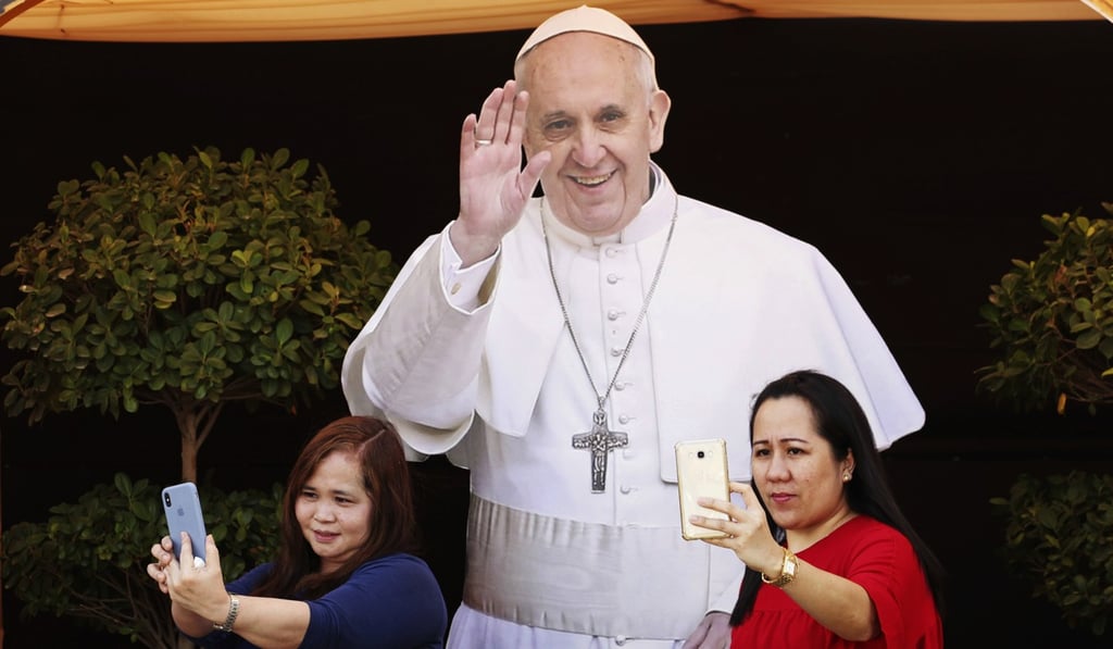 Two parishioners at St Mary’s Catholic Church take selfies in front of a cut-out picture of Pope Francis, in Dubai, the UAE. Photo: AP