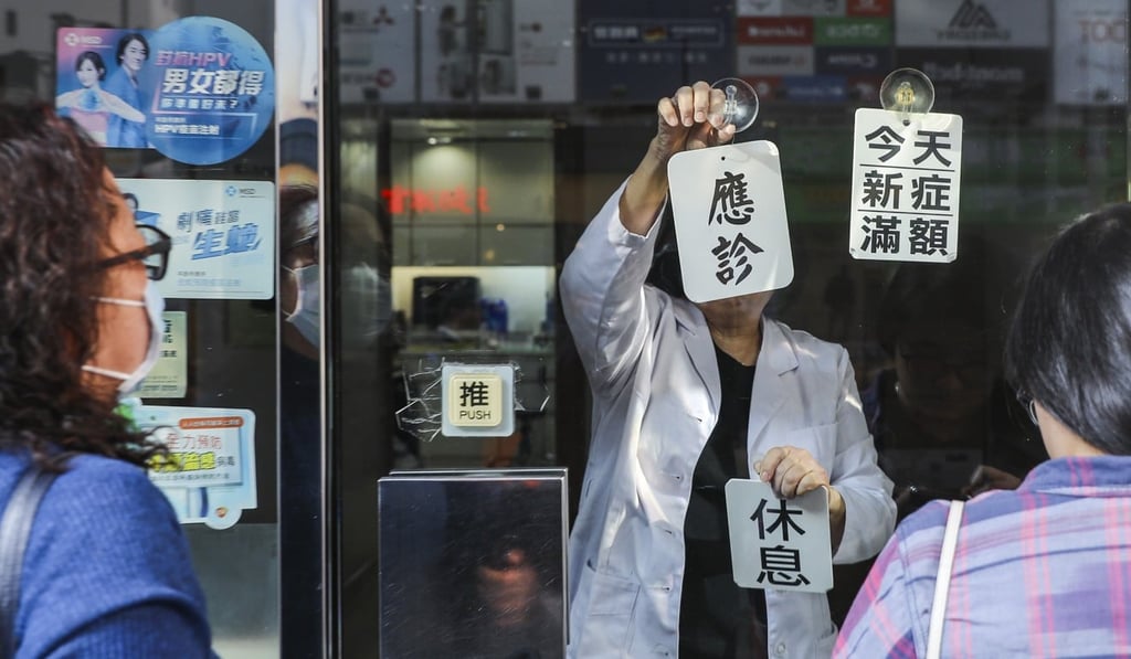 An employee puts up ‘off duty’ and ‘daily visit limit reached’ signs as people queue up outside a clinic in Mong Kok. Photo: Sam Tsang