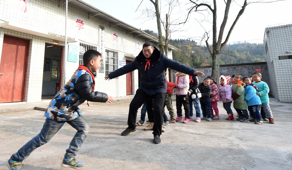 A teacher plays with students at the Gaoshan Village Primary School in Tonggu township of southwest China’s Chongqing municipality. Tan has been teaching students in this remote area for 40 years. He has to take care of both schoolwork and the daily life of students when they are at school, which is more than 5km from the nearest town. Photo: Xinhua
