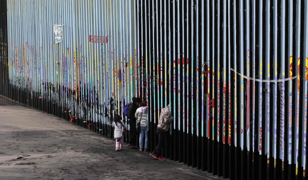 In this file photo taken on January 16, a family of Central American migrants look through the US-Mexico border fence in Baja California state, Mexico. Photo: AFP