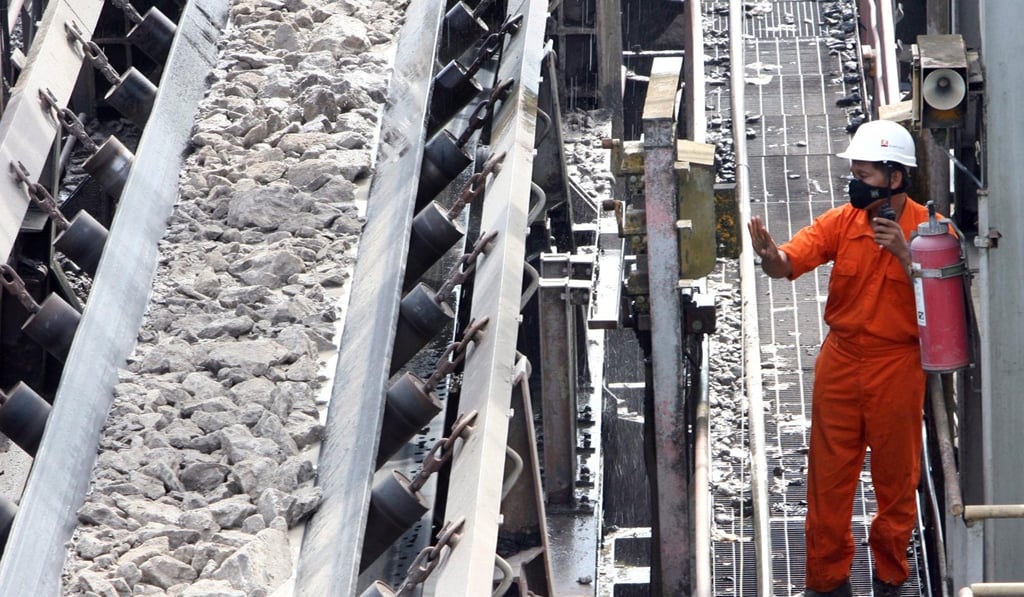 An employee of an Indonesian coal mining company checks a conveyor belt. Photo: EPA