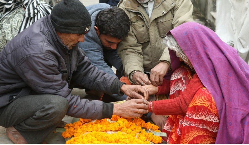 Narmadi Devi (right), 75, blesses the flower-covered body of her husband Halkey Singh Raghuvansi, outside Salvation House. Photo: AFP
