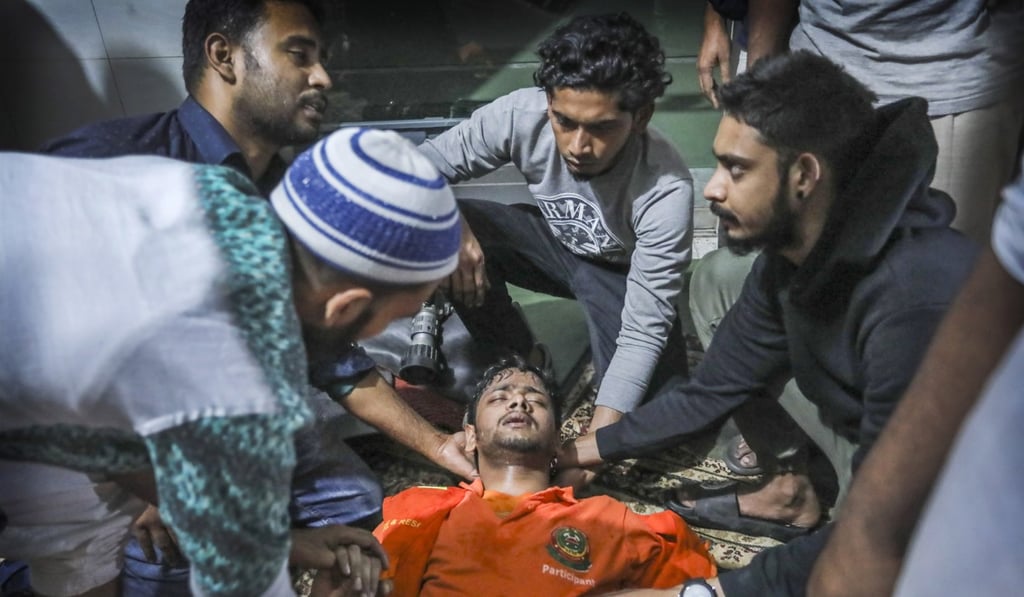 Locals help a Bangladeshi firefighter who lost consciousness briefly. Photo: AP