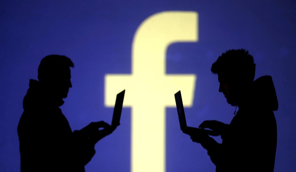 Silhouettes of laptop users in front of a Facebook logo. File photo: Reuters