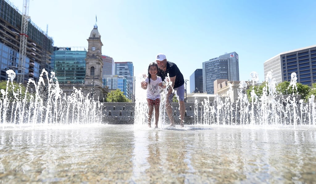 A father and daughter play in a fountain in Adelaide, where n Extreme Heatwave Emergency Warning has been issued. Photo: EPA