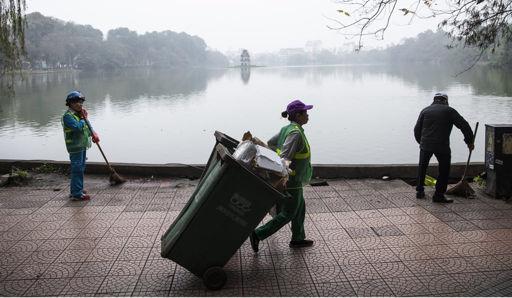 Workers clean a footpath around the Hoan Kiem Lake in Hanoi. Photo: Bloomberg Workers clean a footpath around the Hoan Kiem Lake in Hanoi. Photo: Bloomberg