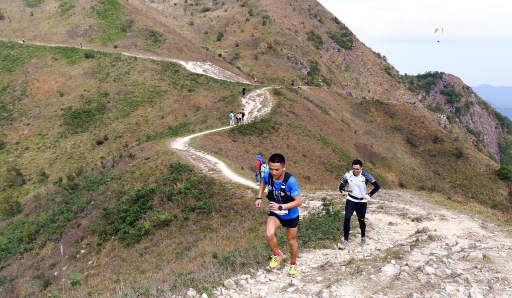 Paragliders circle above Ngong Ping plateau far off in the distance as runners tackle a challenging trail climb during the Vibram Hong Kong 100 Ultra Trail Race. Photo: Vibram HK100 Paragliders circle above Ngong Ping plateau far off in the distance as runners tackle a challenging trail climb during the Vibram Hong Kong 100 Ultra Trail Race. Photo: Vibram HK100