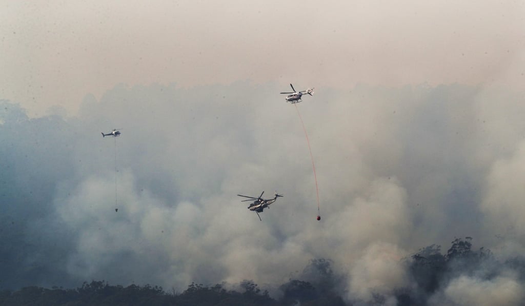 Helicopters drop water on a bush fire in Gippsland, Victoria. Photo: EPA