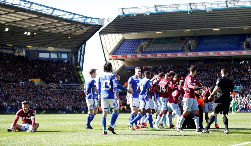 A fan is restrained by a steward and players after invading the pitch and attacking Aston Villa's Jack Grealish (far left).
