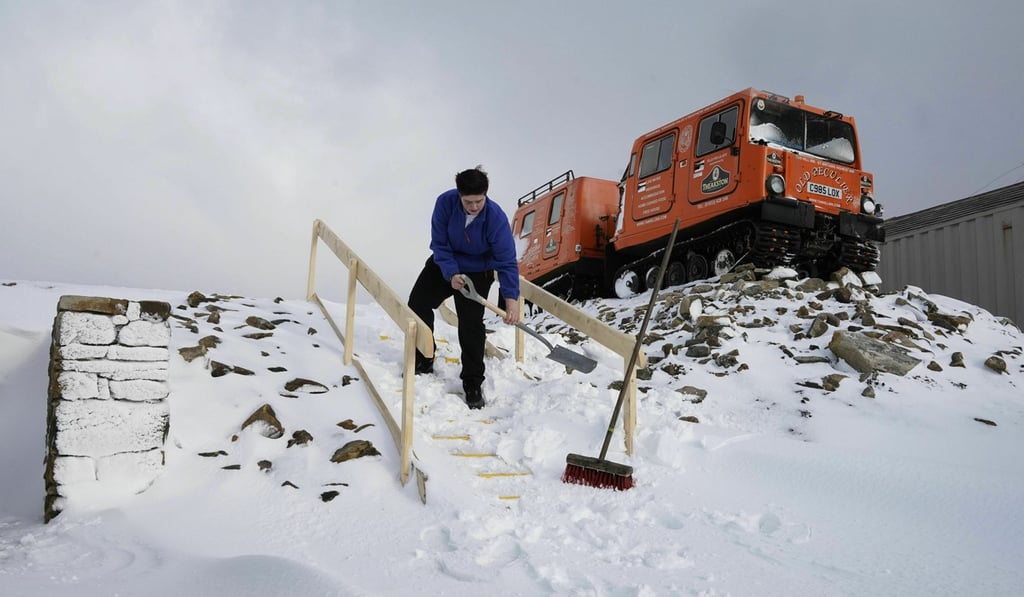 A man clears snow from the steps at the Tan Hill pub in North Yorkshire on March 11, 2019. Photo: AP A man clears snow from the steps at the Tan Hill pub in North Yorkshire on March 11, 2019. Photo: AP