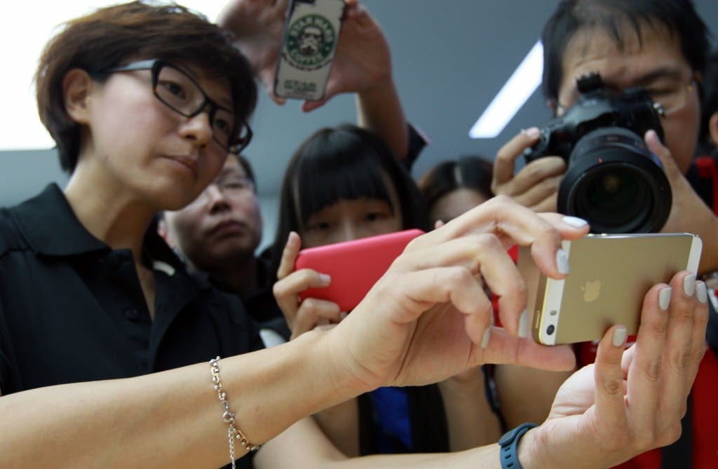 An Apple Store saleswoman holds a gold iPhone in Beijing on September 11, 2013. (Picture: SCMP)