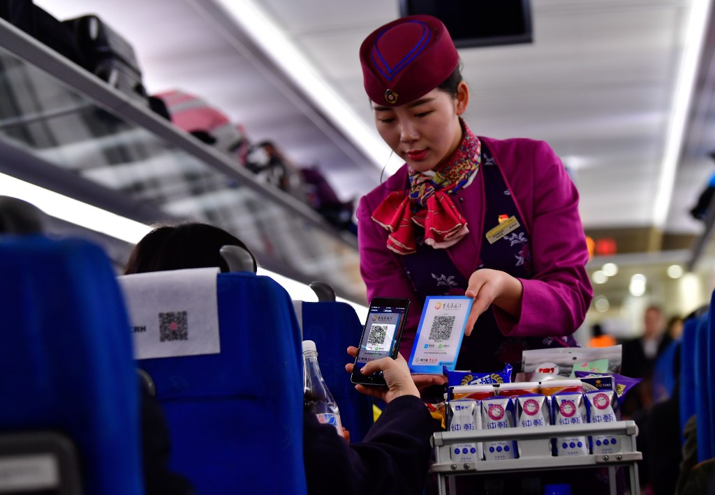 A train passenger scans a QR code to buy a bottle of water. (Picture: Xinhua) A train passenger scans a QR code to buy a bottle of water. (Picture: Xinhua)