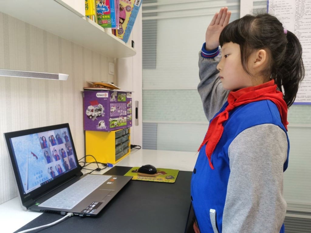A primary school student salutes to the national flag while attending an online flag-raising ceremony at her home in Wuhan, the epicenter of the coronavirus outbreak. (Picture: China News Service)