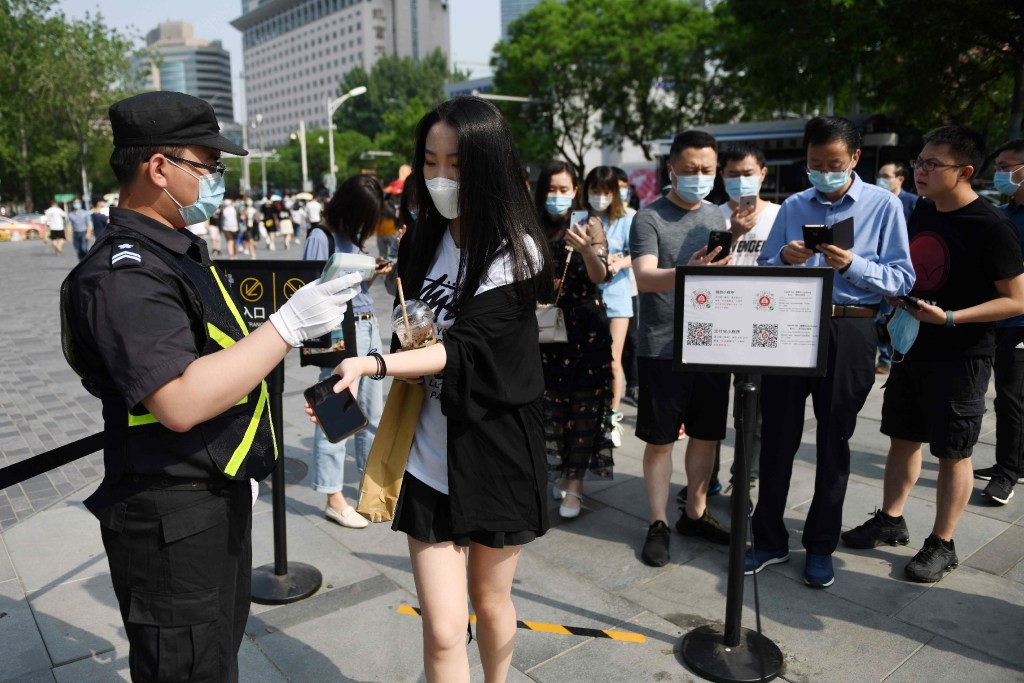 A woman has her temperature taken as others use smartphones to scan a code required to prove their health and travel status before being allowed to enter a shopping mall in Beijing on May 2. (Picture: AFP) A woman has her temperature taken as others use smartphones to scan a code required to prove their health and travel status before being allowed to enter a shopping mall in Beijing on May 2. (Picture: AFP)