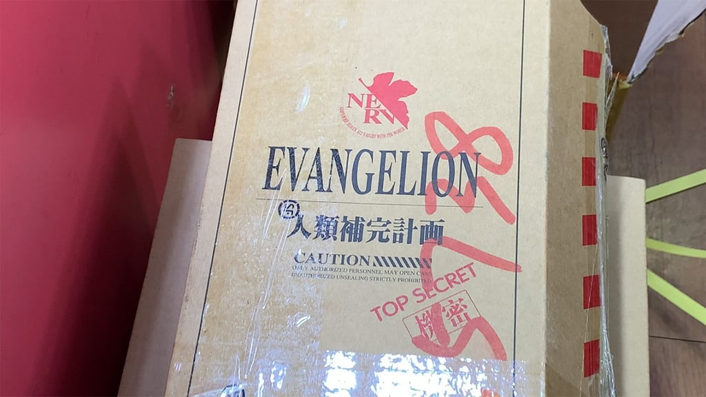 The package is delivered in a cardboard box that says "Human Instrumentality Project,” which is also stamped “Top Secret.” The package is delivered in a cardboard box that says "Human Instrumentality Project,” which is also stamped “Top Secret.”