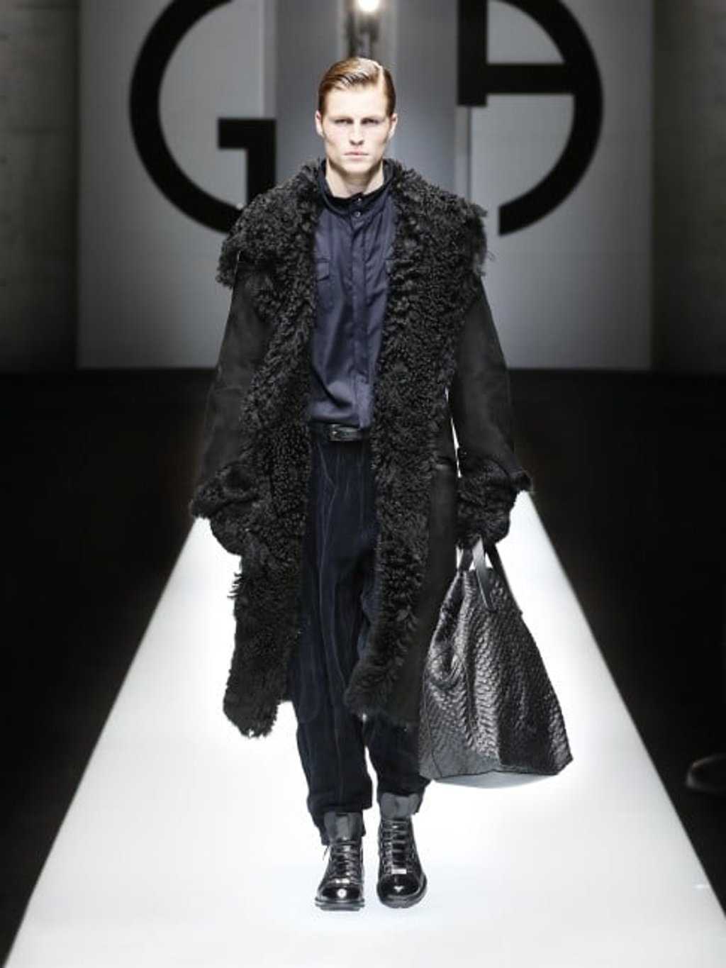 Black long-haired shearling and suede long coat worn over black wool shirt and blue pleated velvet cargo trousers.  Complete the look with black oversized sheepskin gloves.
